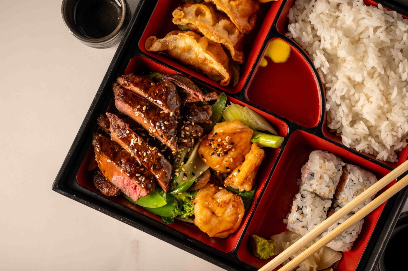 Bento lunch box with teriyaki steak, shrimp, gyoza, California roll and steamed rice - East Moon Centennial CO